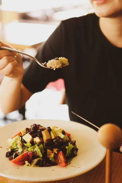 muotokuva houkutteleva valkoihoinen hymyilevä nainen syö salaattia, keskittyä käsin ja haarukka
. - Valokuva, kuva