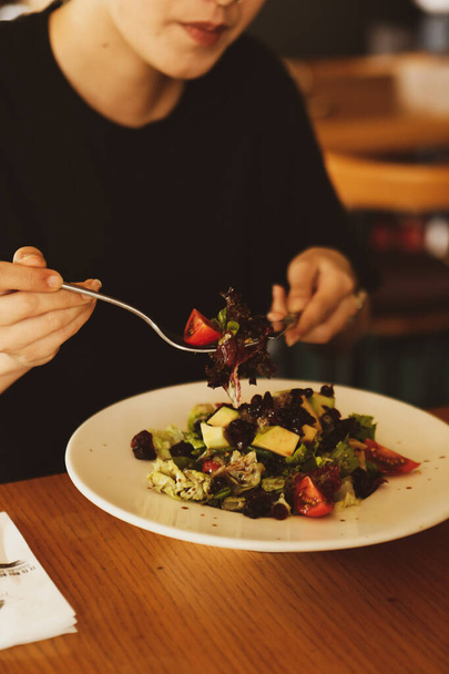 Portrait of attractive caucasian smiling woman eating salad, focus on hand and fork. - Foto, Imagem