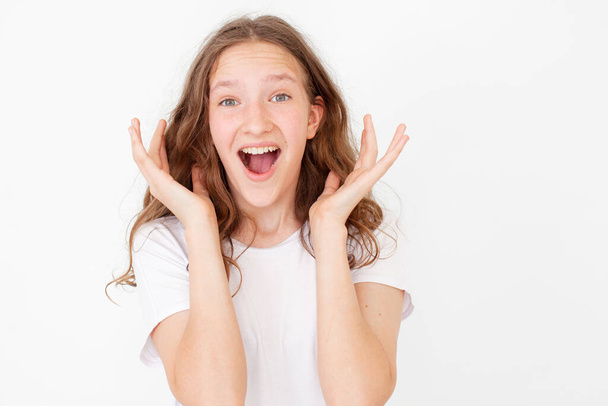 Cheerful happy young beautiful girl looking at camera smiling laughing over white background. Happy teen  in white t-shirt - Foto, Imagen