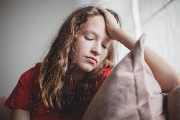 Sad thoughtful teen girl sits on couch feels depressed, offended or lonely, upset young woman suffers from abuse, harassment or heartbreak, grieving lady or violence victim has psychological problem - Photo, Image