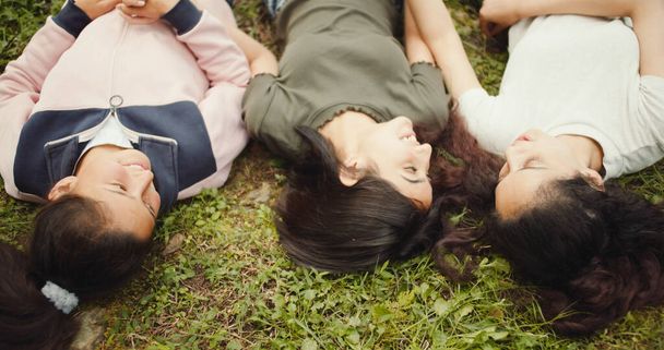 group of happy young women lying on grass in park - Fotografie, Obrázek