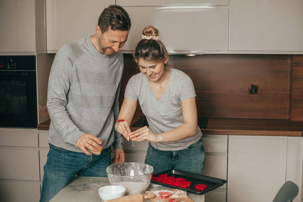 Happy young woman and man baking in kitchen. Young family cooking at home, Teamwork, Young couple have fun, homemade dough, cooking together at home, people have fun - Фото, изображение