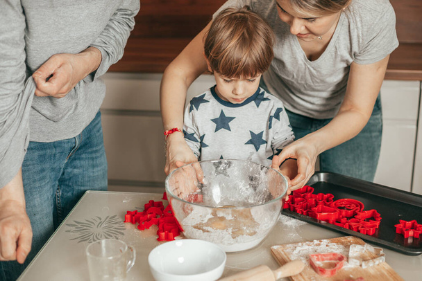 Family with one child cooking in kitchen. Cooking classes for little boy 4 year old, Mother, father and son baking together at home in kitchen. Happy people have fun - Fotoğraf, Görsel