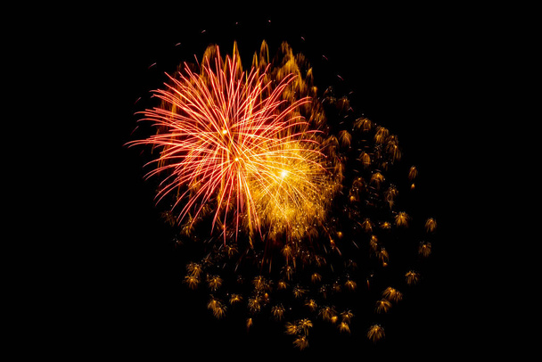 Heldere bloemen van feestelijk vuurwerk op een donkere achtergrond van de nachtelijke hemel - Foto, afbeelding