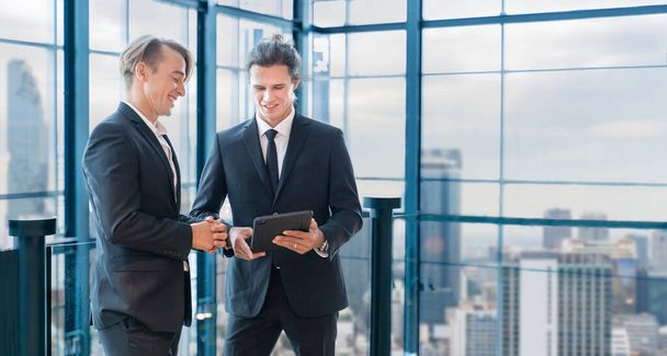 Hombre de negocios caucásico en traje formal discutiendo juntos mientras trabajan en un edificio moderno usando tableta digital - Foto, imagen