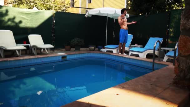 Hombre está hablando por teléfono inteligente durante las vacaciones que van a lo largo de la piscina en el hotel - Metraje, vídeo