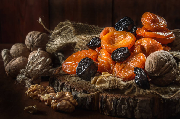 dried apricots, prunes and nuts on a dark wooden background - Photo, Image