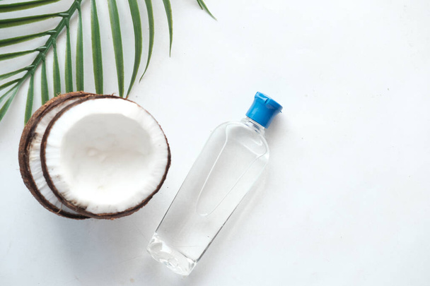 plak verse kokosnoot en fles olie op witte ondergrond  - Foto, afbeelding