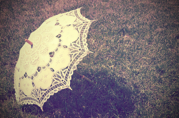 koronkowy parasola na trawie. przyciemniane vintage - Zdjęcie, obraz