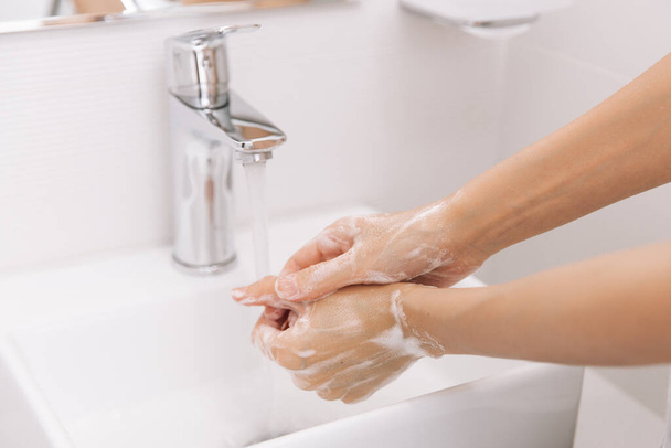 Washing hands under the flowing water tap. Washing hands rubbing with soap for corona virus prevention, hygiene to stop spreading corona virus in or public wash room. Hygiene concept hand detail - Foto, Imagen