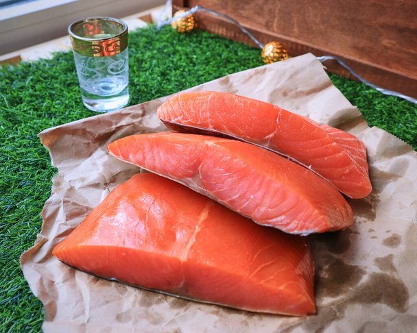 Peixe vermelho na mesa, uma fatia de peixe, frutos do mar e álcool, gramado verde, peixe salgado - Foto, Imagem