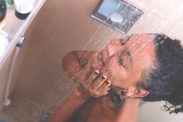 Portret kobiety w łazience myjącej się. Salvador, Bahia, Brazylia. - Zdjęcie, obraz