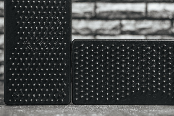Close-up black Sadhu wooden boards with nails for yoga and spiritual practices on the grey background and dark brick wall. The concept of meditation, standing on nails, therapy. - 写真・画像