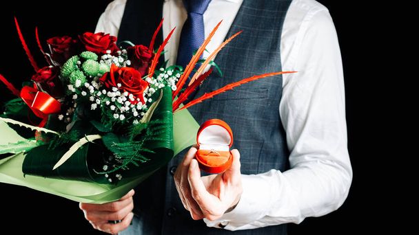 Proposta di matrimonio. Anello di fidanzamento diamante, bouquet di rose rosse in mani da giovane uomo felice. Anello diamante proporre a San Valentino - Foto, immagini