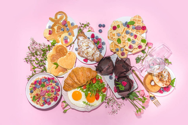 Ημέρα του Αγίου Βαλεντίνου brunch μενού φόντο με διάφορα πιάτα πρωινό και μεσημεριανό γεύμα, βάφλα, κρουασάν, muffins, ντόνατς, μούρα, ομελέτα αυγά, τηγανίτες, ροζ φόντο αντίγραφο χώρου - Φωτογραφία, εικόνα