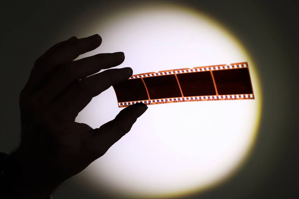 Silhouette of hand holding 35mm photograhic film negatives - Фото, изображение