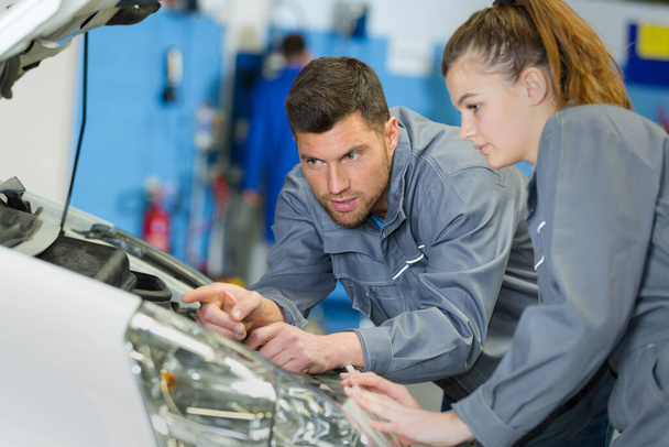 male and female mechanic team examine car engine - Foto, Imagen