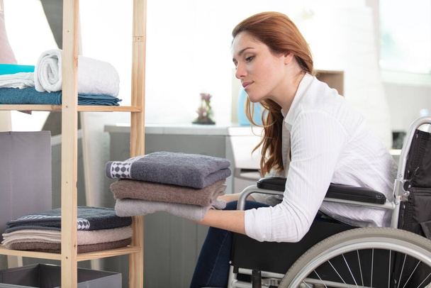 disabled woman putting away laundry in the bathroom - Foto, Imagem
