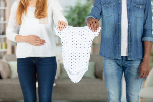 couple holding baby clothes together - Foto, immagini