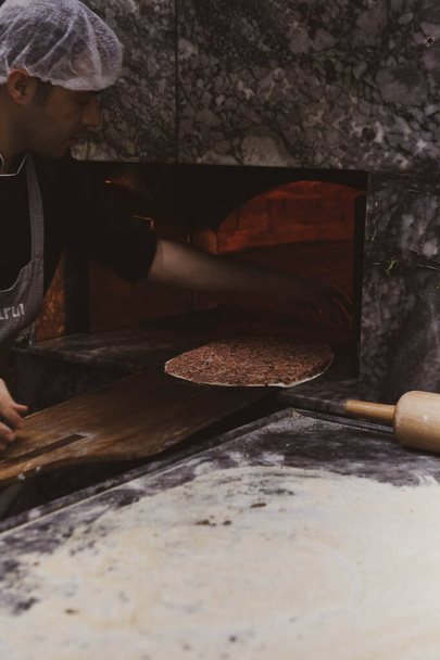 トルコのピザやラハコーンを作る-地中海諸国のファーストフードや人気のあるストリートフード。タルコの皮を調理するための生地、ミンチ肉や野菜成分. - 写真・画像