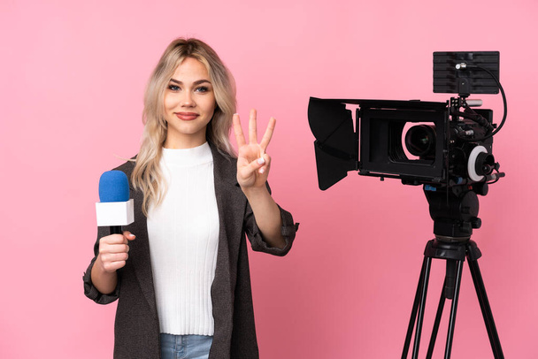 Riporter nő kezében mikrofon és riport hírek izolált rózsaszín háttér boldog és számolás három ujjal - Fotó, kép