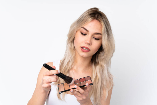 Teenager blonde girl over isolated white background with makeup palette - Photo, Image