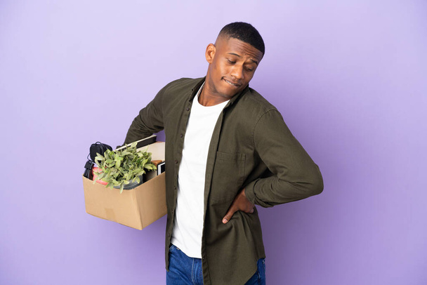 Latin man making a move while picking up a box full of things suffering from backache for having made an effort - 写真・画像