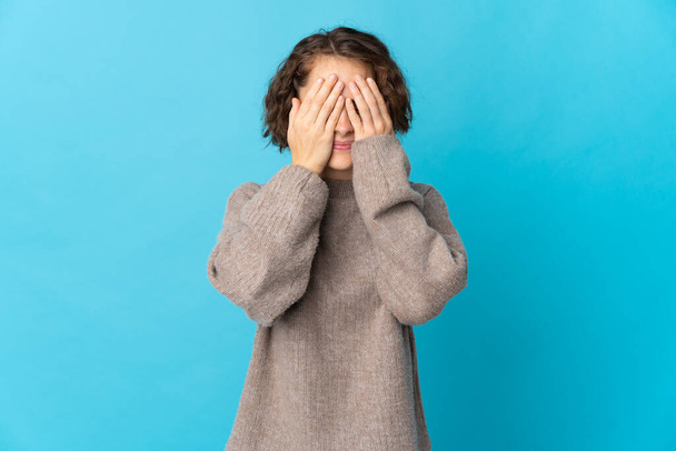 Young English woman isolated on blue background covering eyes by hands - Фото, зображення