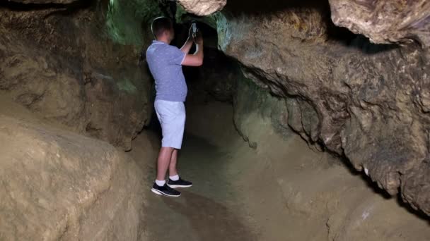 Facet turysta robi zdjęcia jaskiń w lochach. - Materiał filmowy, wideo