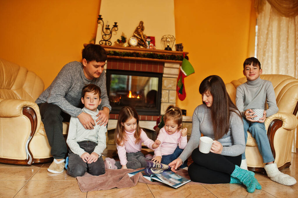 Happy young large family at home by a fireplace in warm living room on winter day.  - Photo, image