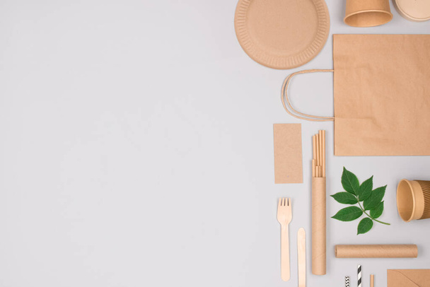 Різні екологічні посуд і крафт-паперова упаковка їжі на сірому фоні. Упаковка для вуличної їжі - чашки, тарілки, соломинки, контейнери та паперові пакети. Макет, плоский лежав
 - Фото, зображення