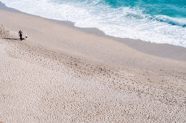 Silhouette egy férfi sétál a kutyájával a parton - Fotó, kép
