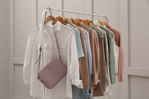 Rack with stylish women's clothes near light wall - Foto, imagen