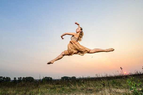 Yang female ballet dancer performs outdoor on sunset. - Zdjęcie, obraz