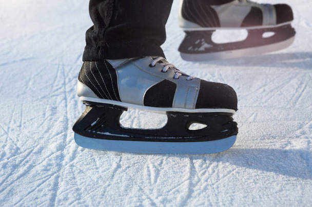 Adult Men's Ice Skates close-up on Ice in Winter outdoor on the move. Rolling and sliding in frosty sunny day, active winter sports and lifestyle - Фото, изображение