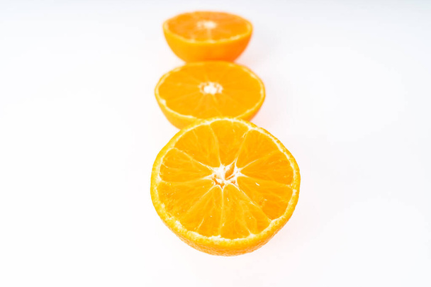 Tres medias mandarinas seguidas sobre un fondo blanco - Foto, imagen