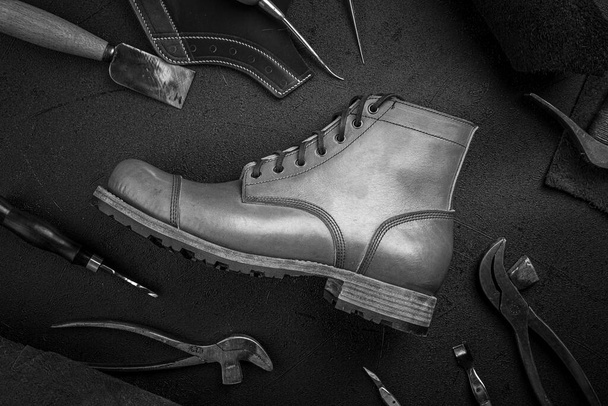 Взуття ручної роботи з коричневої шкіри з інструментами для склеювання
 - Фото, зображення