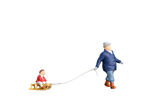 Miniatuur mensen Vader slee slepen met kind geïsoleerd op witte achtergrond met clipping pad - Foto, afbeelding