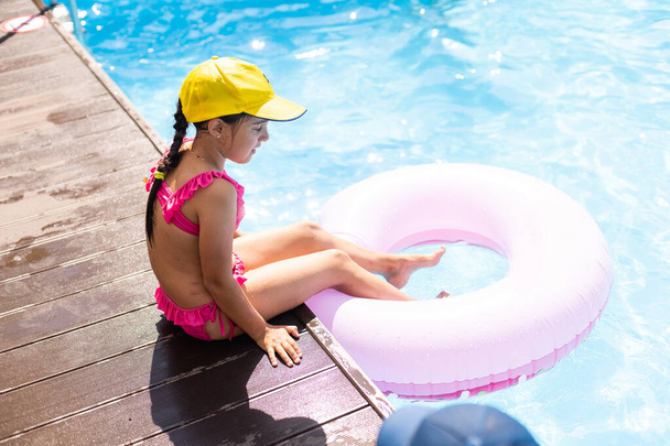 Adorable little girl with inflatable ring at swimming pool - Photo, Image