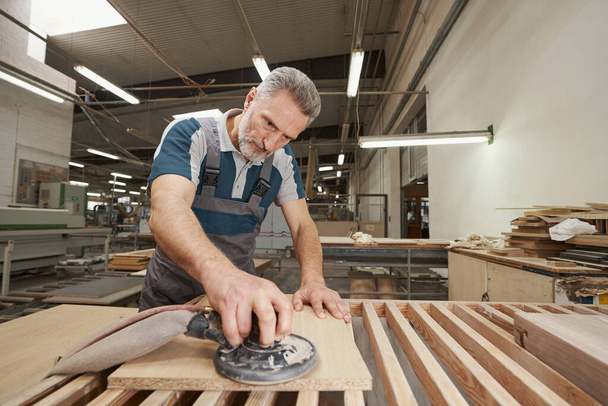 Serious craftsman working at modern furniture manufacture - Zdjęcie, obraz