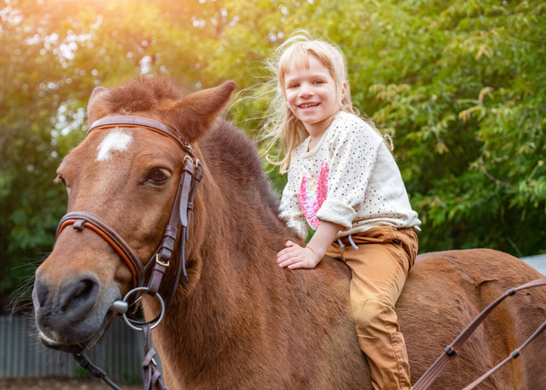 щаслива маленька дівчинка верхи на коні без сідла
 - Фото, зображення
