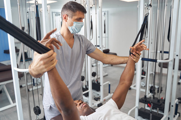 Rehabilitation physician working with patient at gym - Fotó, kép