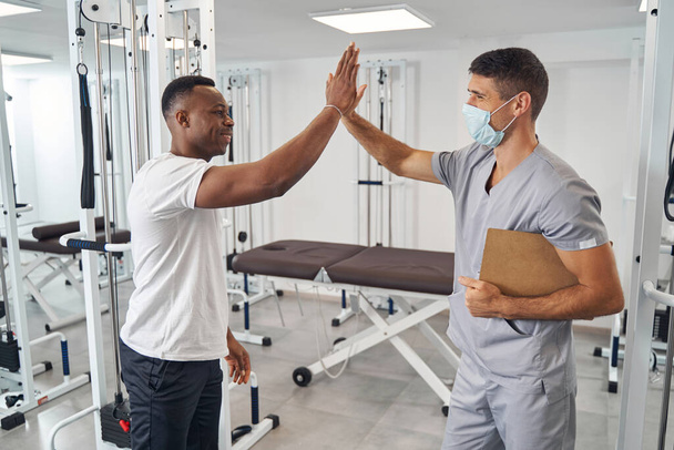 Young man and his physical therapist slapping palms - Foto, Bild