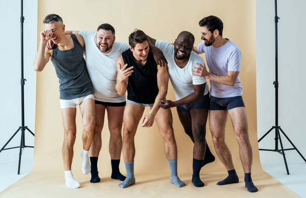 group of multiethnic men posing for a male edition body positive beauty set. guys with different age, and body wearing boxers underwear - Foto, Imagem