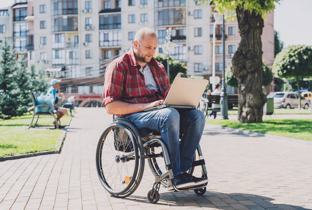 Freelancer with a physical disability who uses wheelchair working at the park - Foto, afbeelding