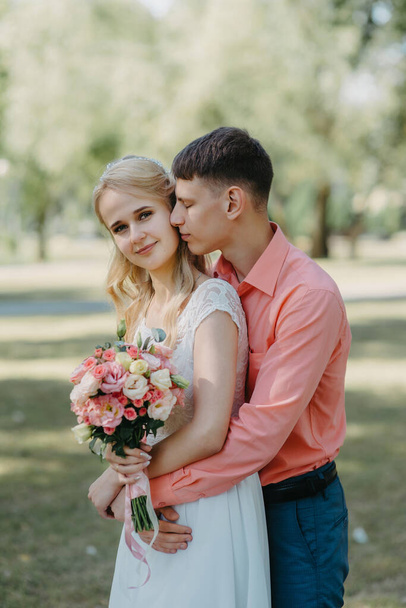 Bride and groom at wedding Day walking Outdoors on spring nature. Bridal couple, Happy Newlywed woman and man embracing in green park. Loving wedding couple outdoor. Wedding shot of bride and groom in - Foto, imagen