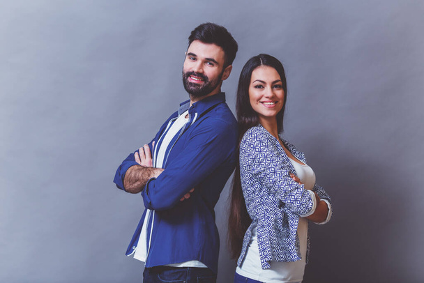 Jeune beau couple posant en studio, exprimant émotions et gestes, souriant, sur fond gris
 - Photo, image
