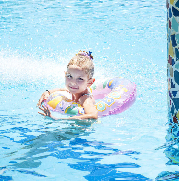 A kislány úszik egy körrel a medencében. - Fotó, kép