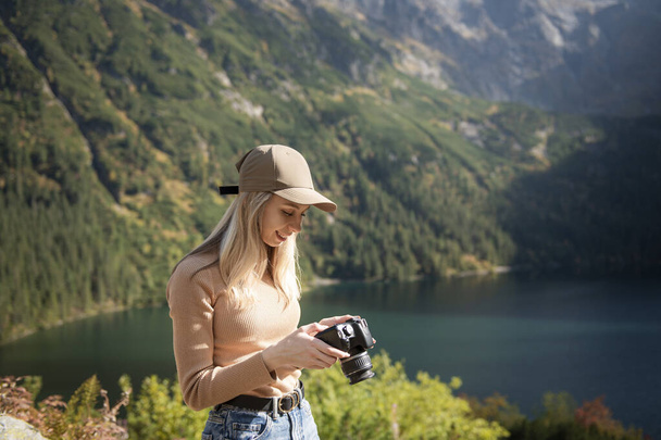 Fotograf turystyczny podróżnik stojący na zielonym szczycie góry trzymając w ręku cyfrowy aparat fotograficzny. Turysta biorąc fotografię, dziewczyna cieszyć krajobraz panoramiczny natury w podróży, relaks i wakacje koncepcja - Zdjęcie, obraz