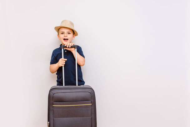 Happy kid boy  are carrying a big suitcase on a white background, and expecting the big vacation - Photo, Image
